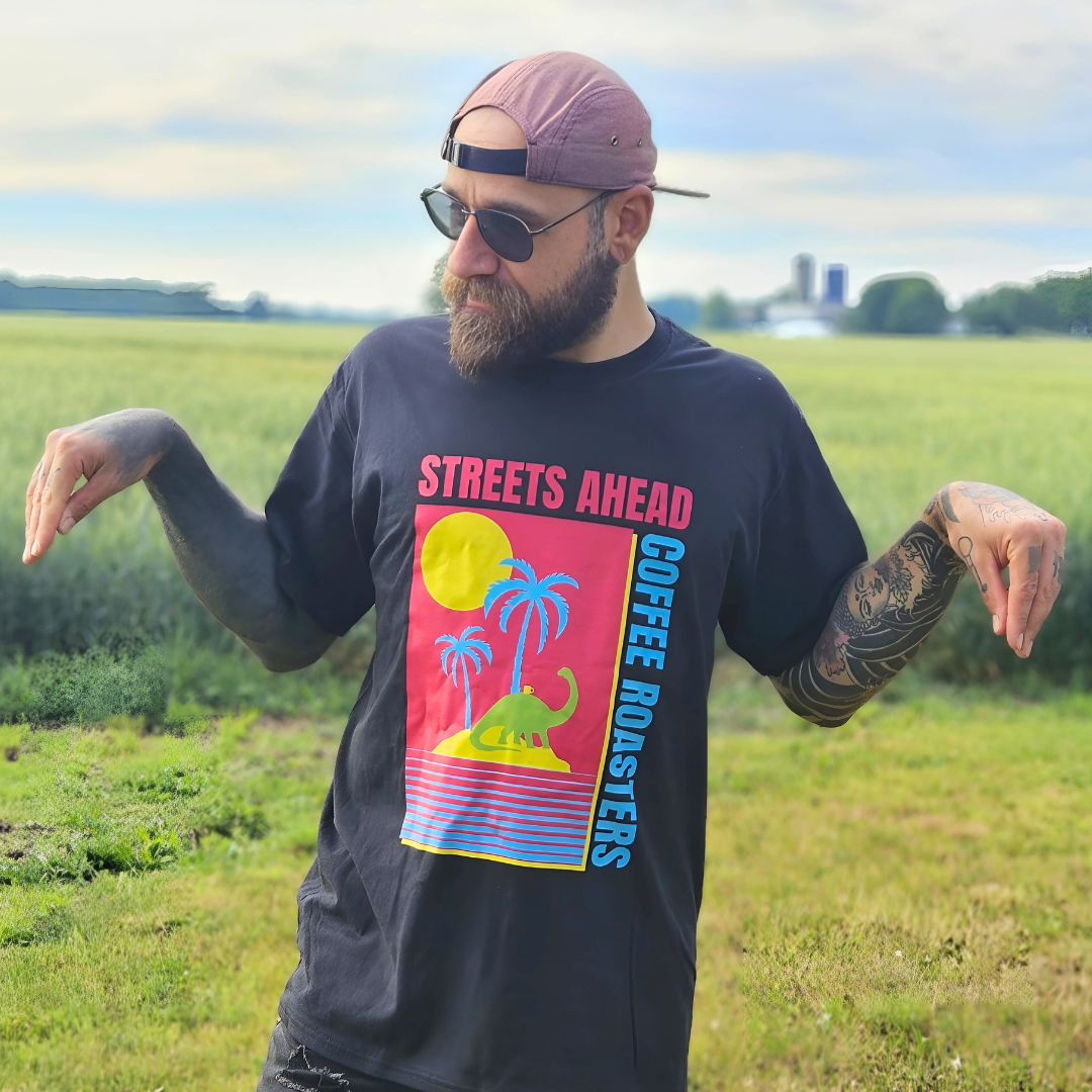 Man wearing a black t-shirt with colorful graphic design in an open field