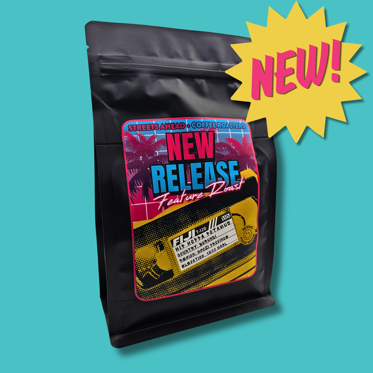 A black coffee roast bag with a colorful front label reading 'NEW RELEASE Features Roast'shown on a turquoise background with a yellow starburst 'NEW!' graphic.