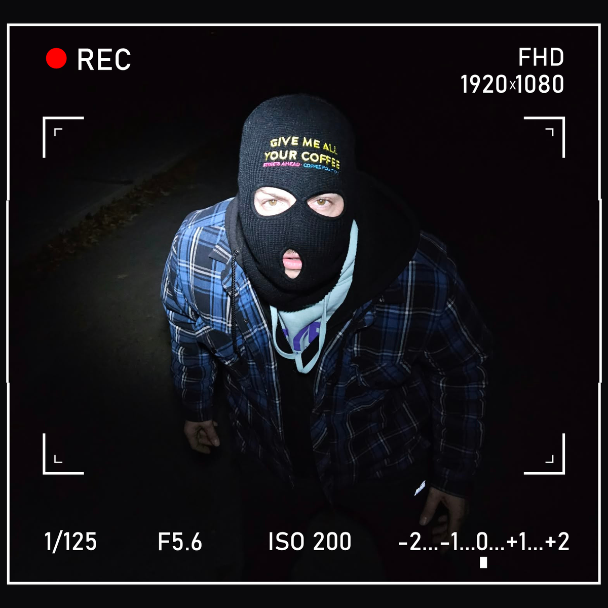 Masked person in balaclava reading "Give me all your coffee Streets Ahead Coffee Roasters", plaid jacket, camera frame overlay and bold "Have you seen this man?" header