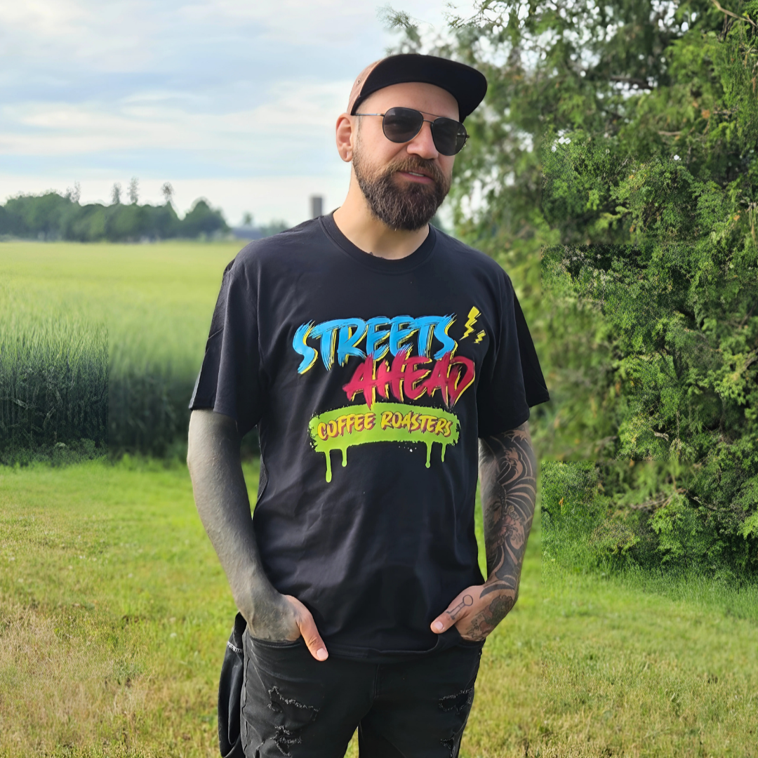 Man wearing a black t-shirt with colorful text in an outdoor setting