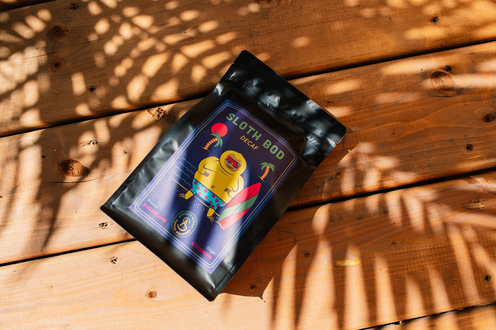 Coffee bag with sloth illustration on a wooden surface